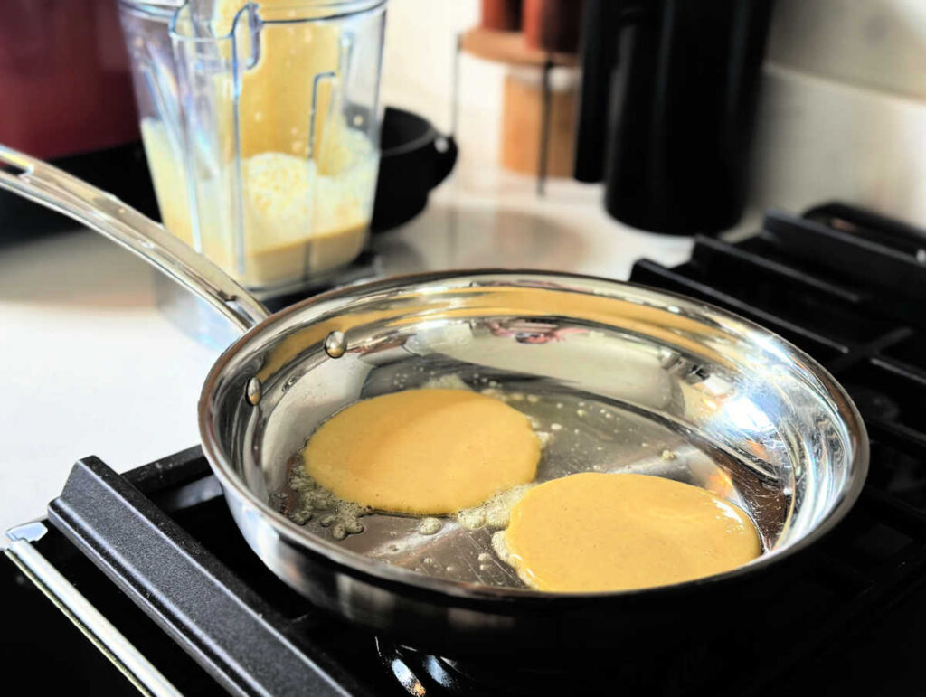 pancake batter on a skillet, making pancakes on the stove top